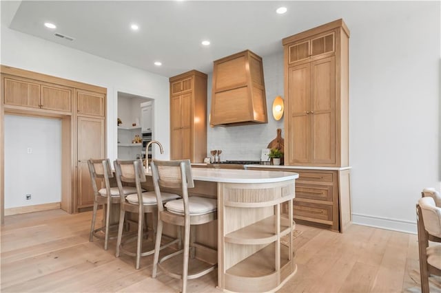 1816 NE Lashbrook Cir, Lees Summit, MO 64086 - kitchen featuring open shelves, visible vents, premium range hood, light wood-type flooring, and tasteful backsplash