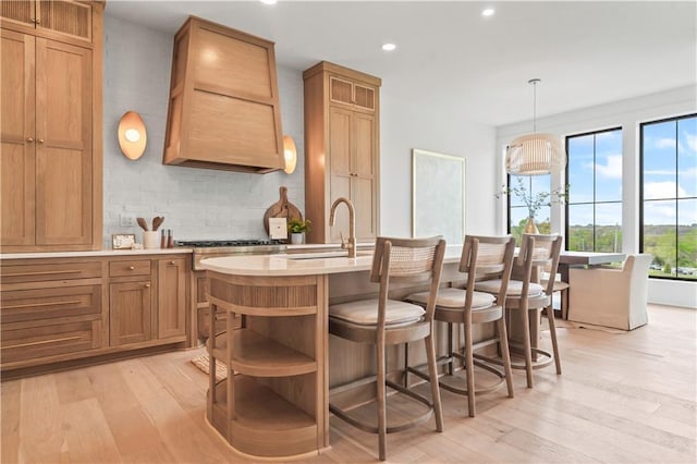 1816 NE Lashbrook Cir, Lees Summit, MO 64086 - kitchen featuring open shelves, a kitchen island with sink, light wood-style flooring, backsplash, and recessed lighting