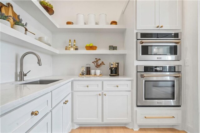 1816 NE Lashbrook Cir, Lees Summit, MO 64086 - kitchen with white cabinets, a sink, open shelves, light stone countertops, and double oven