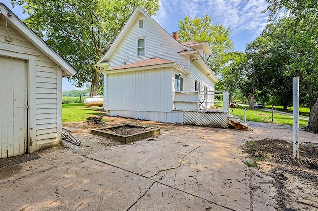 view of side of home with a wooden deck, a lawn, and an outbuilding