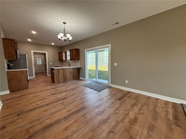 kitchen with tasteful backsplash, sink, light hardwood / wood-style flooring, an inviting chandelier, and hanging light fixtures