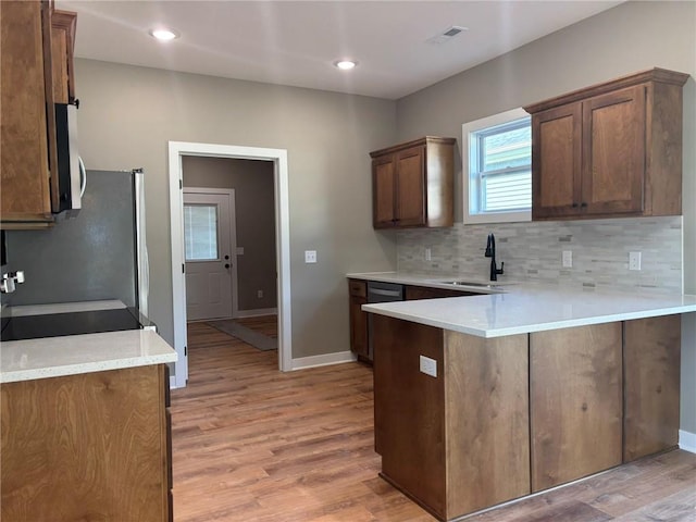 kitchen with kitchen peninsula, sink, light hardwood / wood-style floors, and appliances with stainless steel finishes