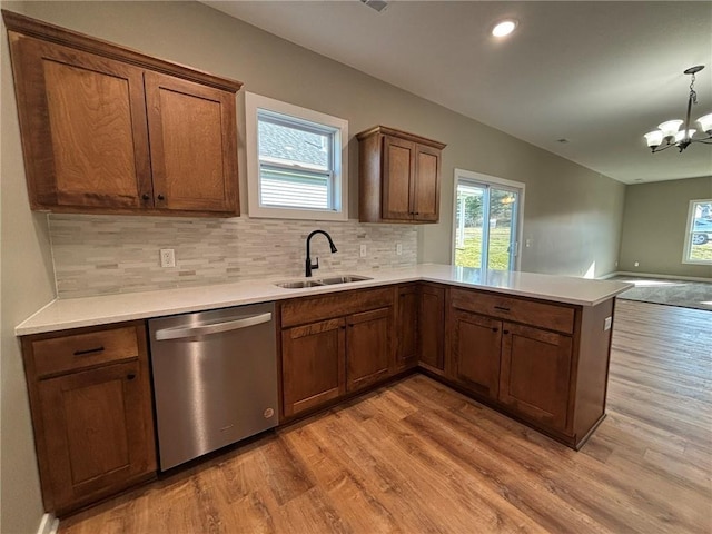 kitchen with sink, light hardwood / wood-style flooring, dishwasher, a chandelier, and hanging light fixtures