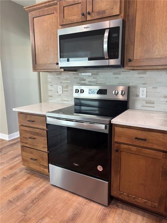 kitchen featuring light wood-type flooring, stainless steel appliances, and tasteful backsplash