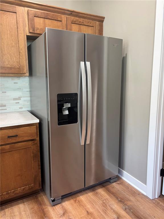 kitchen with tasteful backsplash, stainless steel fridge, and light hardwood / wood-style floors