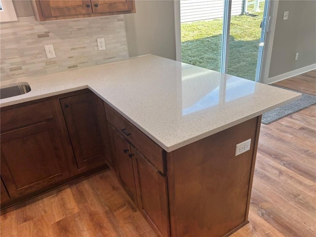 kitchen with tasteful backsplash, light stone counters, and light hardwood / wood-style floors