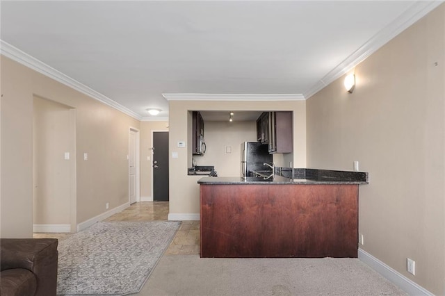 kitchen featuring fridge, crown molding, kitchen peninsula, dark stone countertops, and light carpet