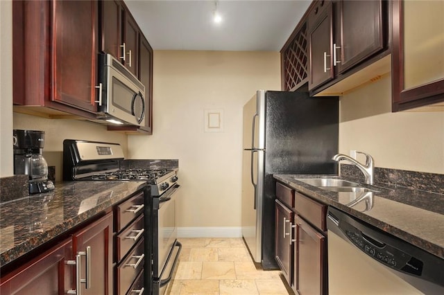 kitchen featuring sink, dark stone countertops, light tile patterned floors, and stainless steel appliances