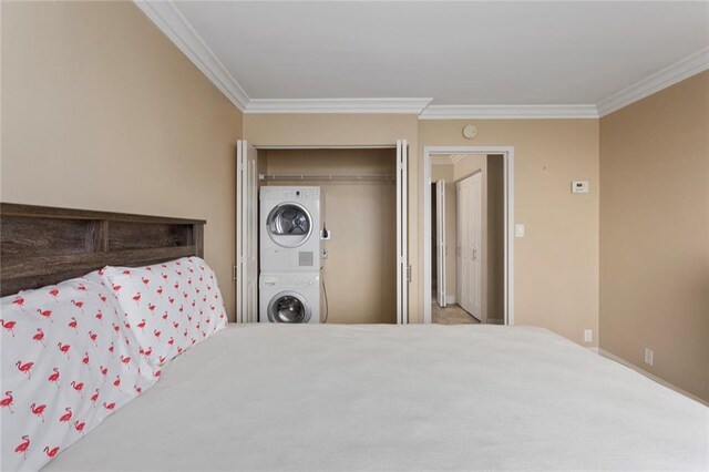 bedroom with stacked washing maching and dryer, crown molding, and a closet