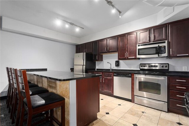 kitchen featuring appliances with stainless steel finishes, light tile patterned flooring, a kitchen island, and rail lighting