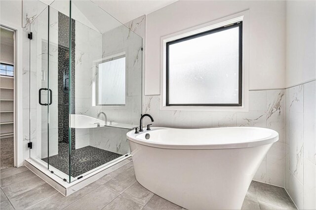 bathroom with shower with separate bathtub, tile walls, vaulted ceiling, and plenty of natural light