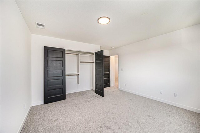 unfurnished bedroom featuring a closet and light colored carpet