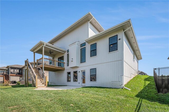 rear view of house featuring a patio, a wooden deck, and a lawn