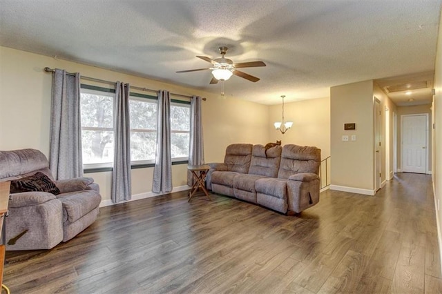 living room with dark hardwood / wood-style flooring, ceiling fan with notable chandelier, and a textured ceiling