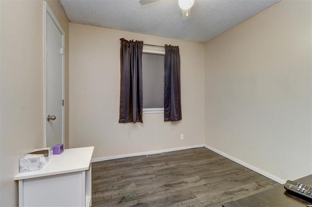 empty room with ceiling fan, dark hardwood / wood-style floors, and a textured ceiling