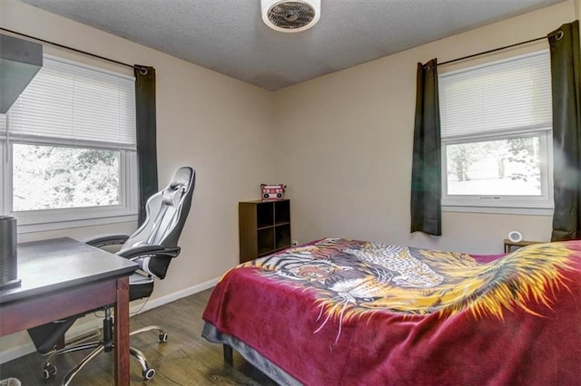 bedroom featuring multiple windows, hardwood / wood-style floors, and a textured ceiling