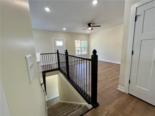 stairs with hardwood / wood-style flooring and ceiling fan