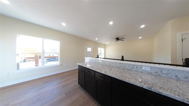 kitchen featuring baseboards, light stone countertops, dark cabinetry, light wood-style floors, and recessed lighting