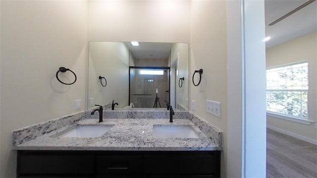 full bath featuring double vanity, baseboards, and a sink