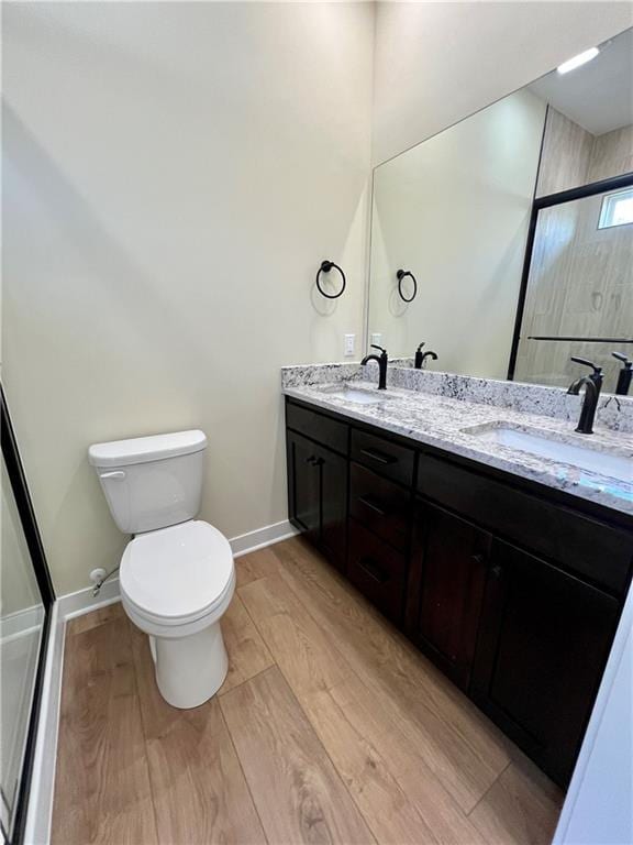 full bath with a sink, baseboards, toilet, and wood finished floors