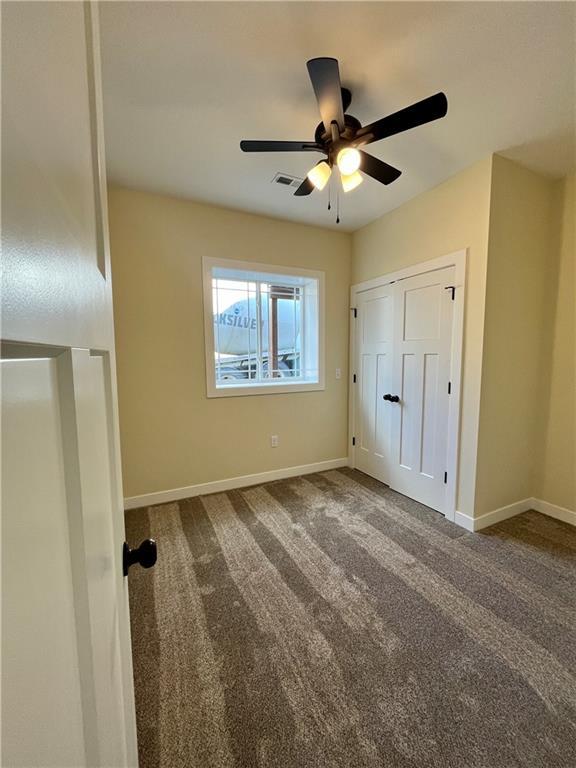 unfurnished bedroom featuring visible vents, a ceiling fan, baseboards, and carpet floors