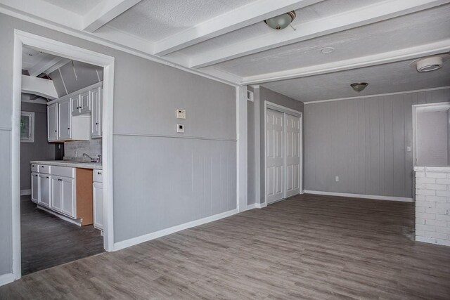 unfurnished room with dark hardwood / wood-style flooring, beam ceiling, and a textured ceiling