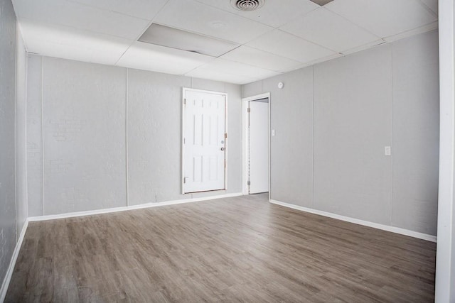 unfurnished room featuring visible vents, wood finished floors, a paneled ceiling, and baseboards