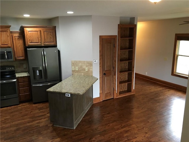 kitchen with kitchen peninsula, dark hardwood / wood-style floors, appliances with stainless steel finishes, and decorative backsplash