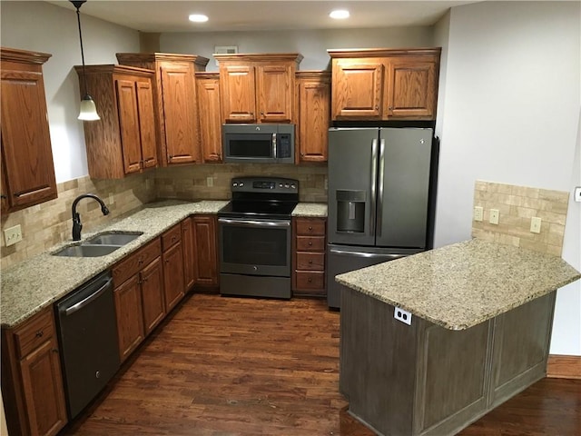 kitchen with hanging light fixtures, appliances with stainless steel finishes, dark hardwood / wood-style flooring, sink, and kitchen peninsula