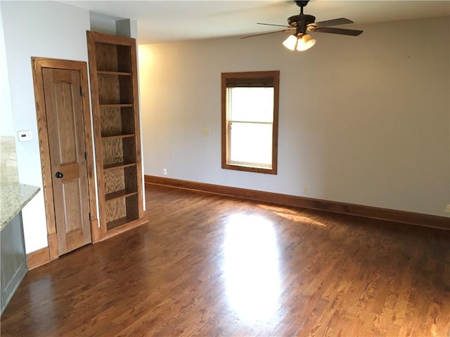 spare room with dark hardwood / wood-style flooring and ceiling fan