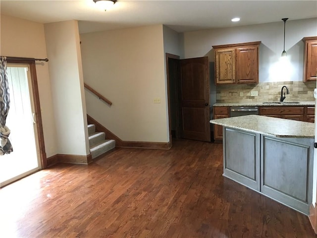 kitchen with decorative light fixtures, dark hardwood / wood-style flooring, dishwasher, backsplash, and sink