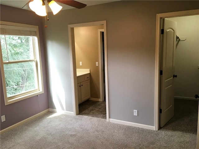 unfurnished bedroom with ensuite bath, multiple windows, ceiling fan, and light colored carpet