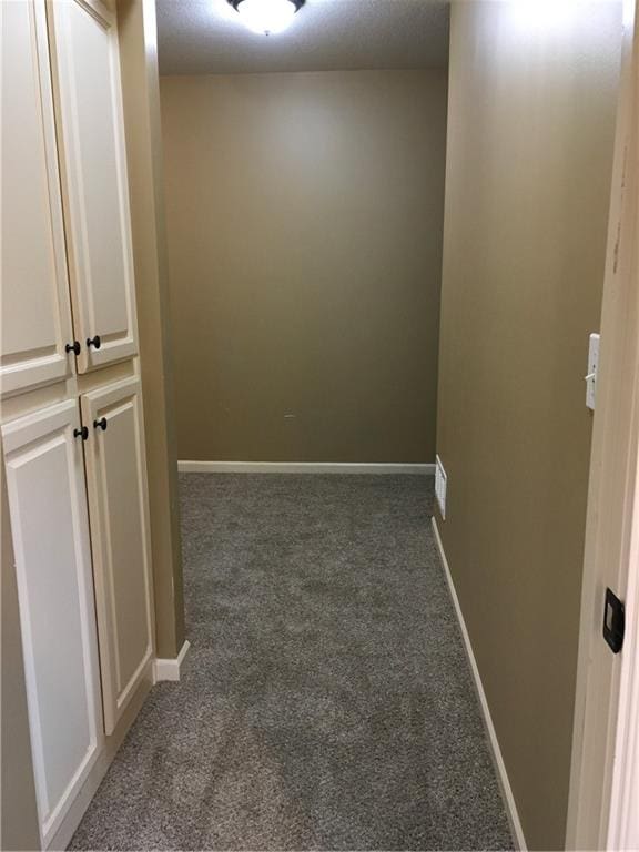 hallway featuring dark colored carpet