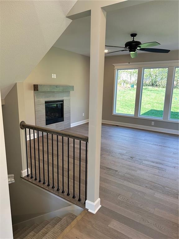 living area with a tiled fireplace, plenty of natural light, baseboards, and wood finished floors