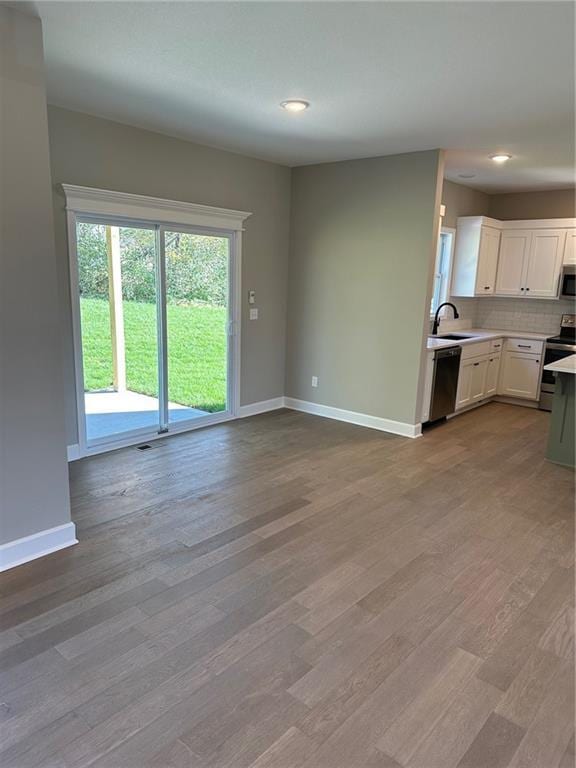 unfurnished living room with a sink, light wood-style flooring, and baseboards