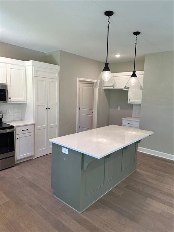 kitchen with a center island, light countertops, hanging light fixtures, appliances with stainless steel finishes, and white cabinetry