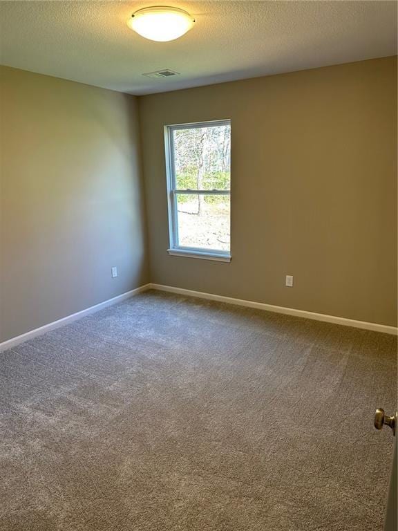 spare room with carpet floors, visible vents, and baseboards