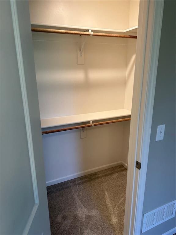 walk in closet with dark carpet and built in study area