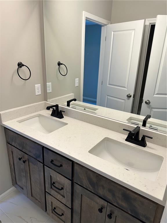 bathroom featuring marble finish floor, double vanity, and a sink