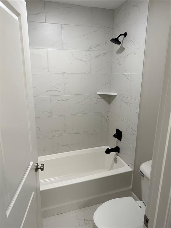 bathroom with toilet, marble finish floor, and tub / shower combination