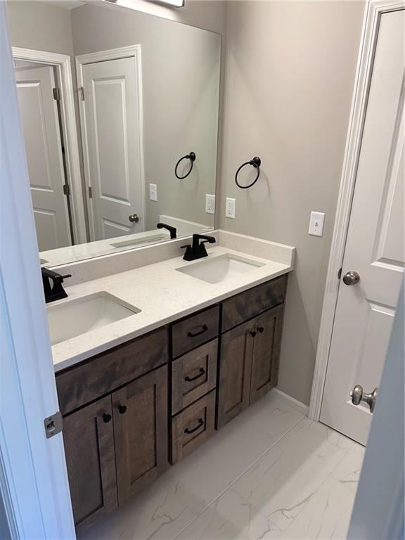 bathroom with double vanity, marble finish floor, and a sink