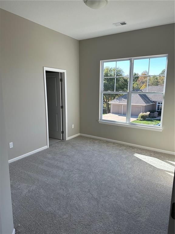 carpeted spare room featuring visible vents and baseboards