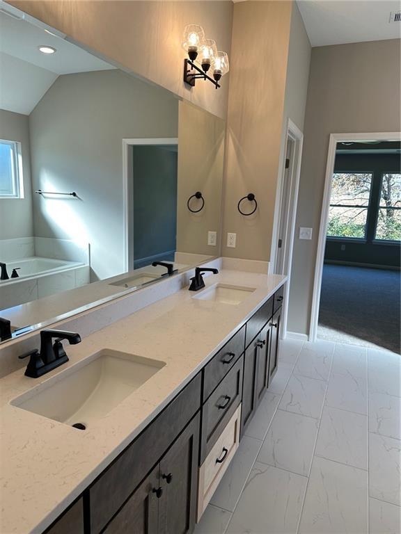 full bathroom featuring marble finish floor, a sink, and double vanity