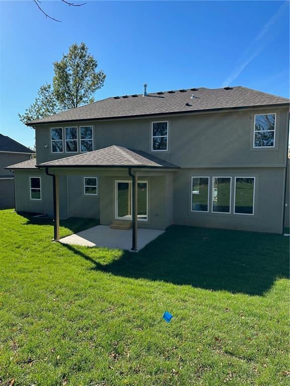 rear view of property with a lawn, a patio, and stucco siding