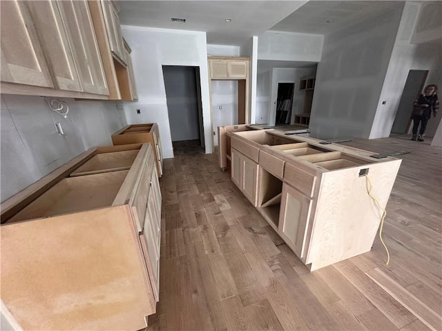 kitchen with light brown cabinets, light hardwood / wood-style flooring, and a kitchen island