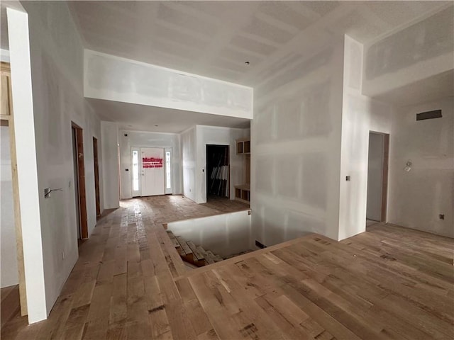 hallway with hardwood / wood-style floors and a towering ceiling