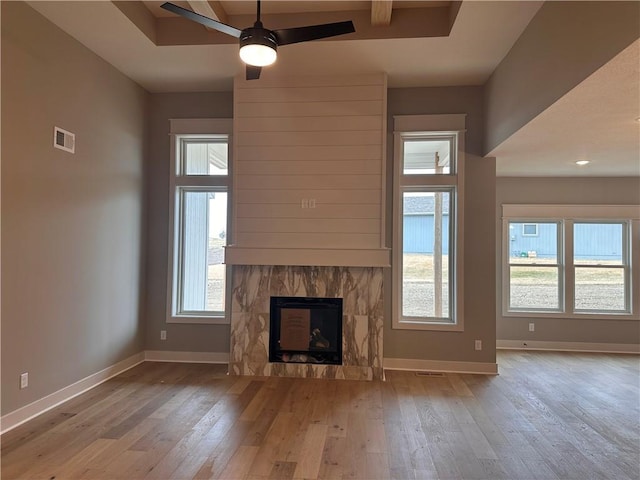 unfurnished living room featuring light hardwood / wood-style flooring, a raised ceiling, and ceiling fan