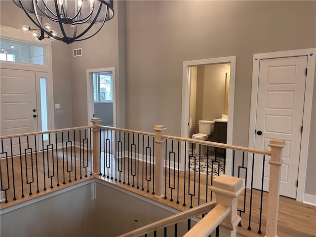 hall with an inviting chandelier, a towering ceiling, and light hardwood / wood-style flooring