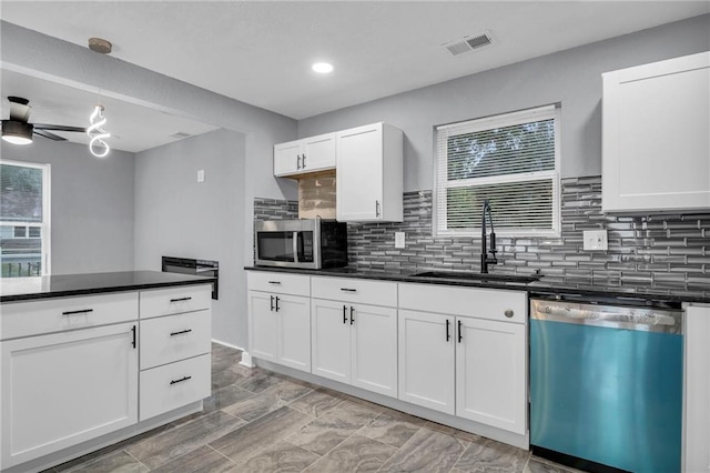 kitchen featuring ceiling fan, decorative backsplash, white cabinetry, sink, and stainless steel appliances