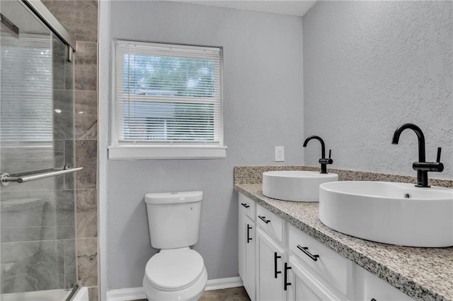 6825 Walrond Ave, Kansas City, MO 64132 - bathroom featuring double vanity, tiled shower, toilet, and a textured wall